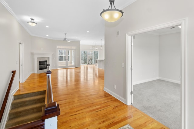 unfurnished living room featuring light wood finished floors, baseboards, crown molding, a fireplace, and recessed lighting