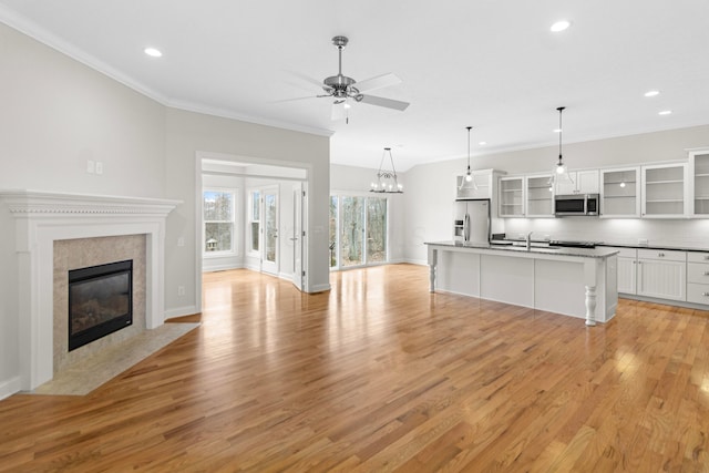 kitchen with crown molding, stainless steel appliances, a high end fireplace, white cabinetry, and light wood-type flooring