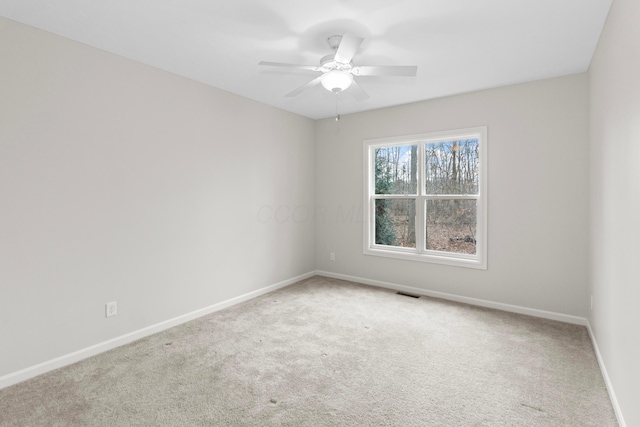 spare room with carpet floors, baseboards, visible vents, and ceiling fan