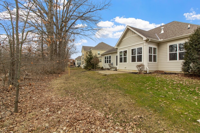 rear view of property with a lawn, a patio area, and board and batten siding