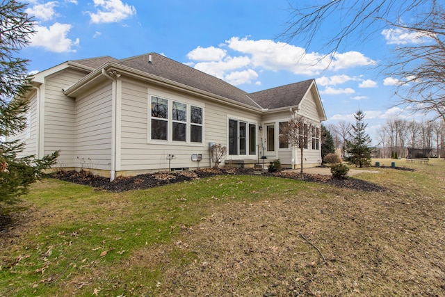 back of house featuring a shingled roof, a sunroom, and a lawn