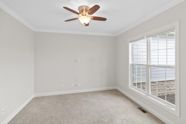 spare room with a wealth of natural light, light carpet, crown molding, and visible vents