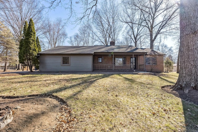 view of front of home with a front lawn, a porch, brick siding, and a chimney