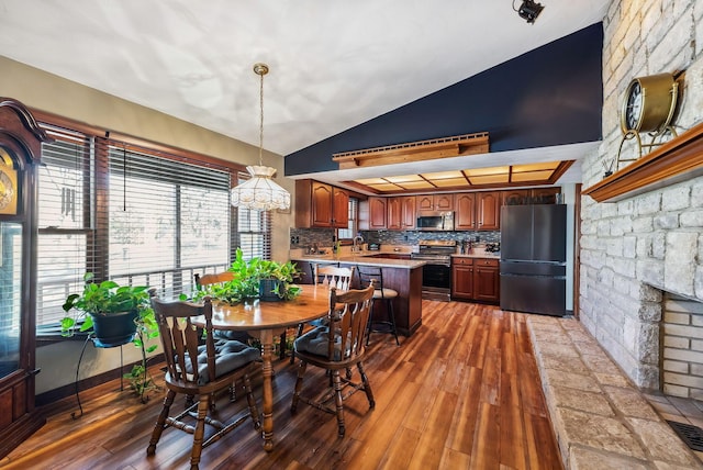 dining room featuring visible vents, lofted ceiling, a large fireplace, and wood finished floors