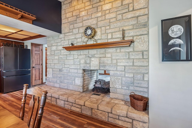 kitchen featuring a fireplace, wood finished floors, freestanding refrigerator, and ornamental molding