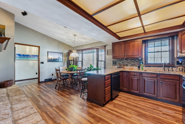 kitchen with light wood finished floors, a healthy amount of sunlight, dishwashing machine, a peninsula, and a sink