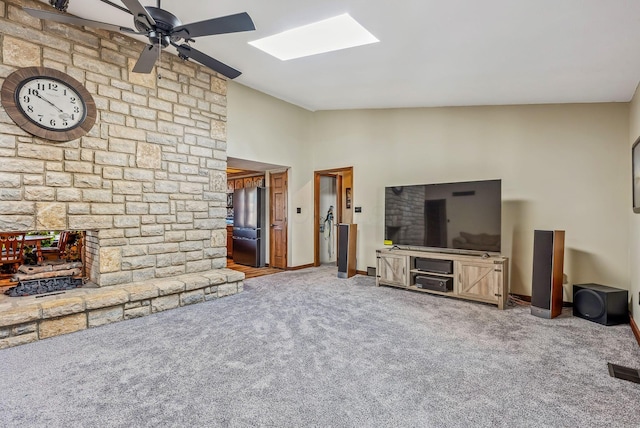 living area with baseboards, lofted ceiling with skylight, ceiling fan, and carpet flooring