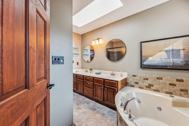 full bathroom with a sink, a tub with jets, a skylight, and double vanity