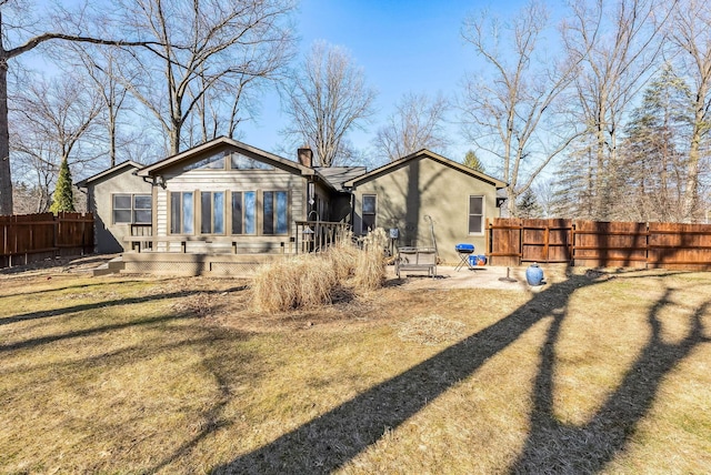 back of property featuring a chimney, a yard, and fence