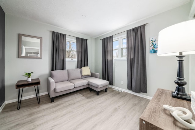 living room featuring light wood-style flooring, baseboards, and a textured ceiling