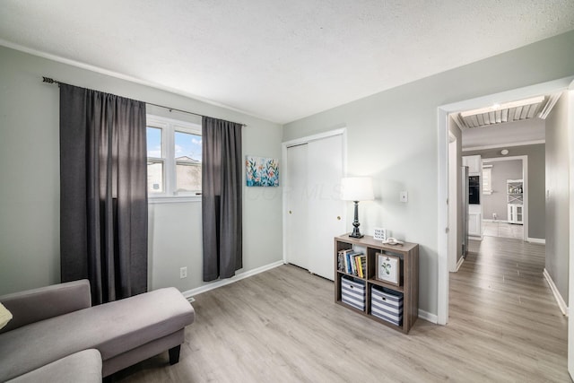 sitting room with light wood-type flooring, baseboards, visible vents, and a textured ceiling