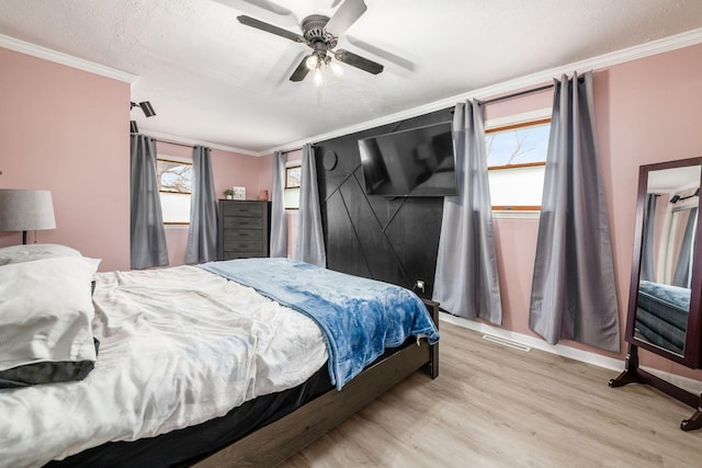 bedroom featuring light wood-style flooring, a textured ceiling, visible vents, and crown molding