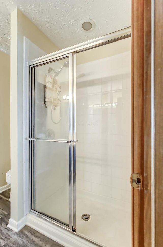 3093 Briar Ridge Rd, Columbus, OH 43232 - bathroom featuring a stall shower, a textured ceiling, toilet, and wood finished floors