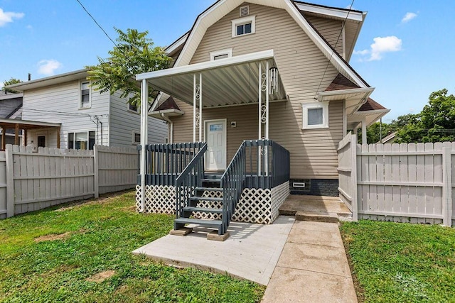 rear view of property featuring a porch, a lawn, fence, and a gambrel roof