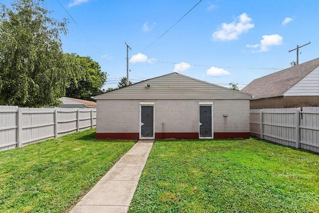 back of property with concrete block siding, a fenced backyard, and a yard