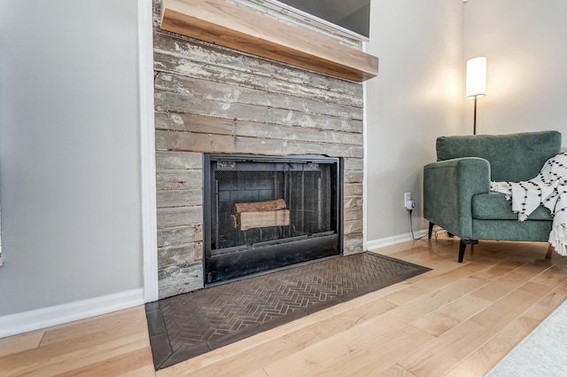 sitting room featuring wood finished floors, a fireplace with flush hearth, and baseboards