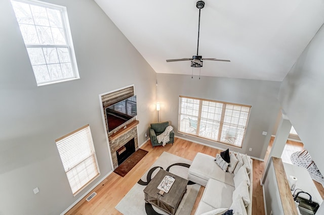 living area with light wood-type flooring, a fireplace, visible vents, and a healthy amount of sunlight