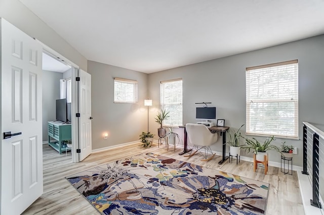 office space with beverage cooler, light wood-style flooring, and baseboards