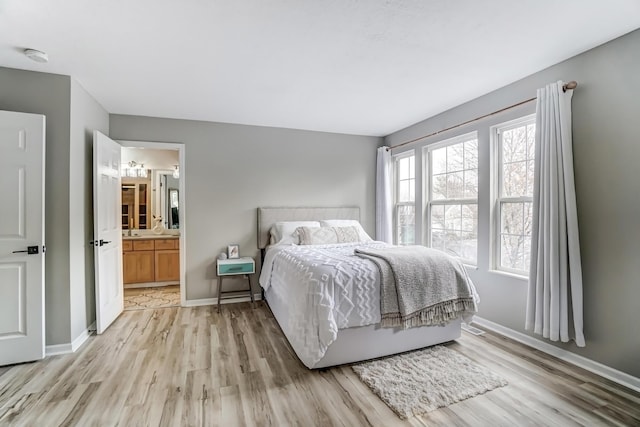 bedroom with light wood finished floors, baseboards, and connected bathroom