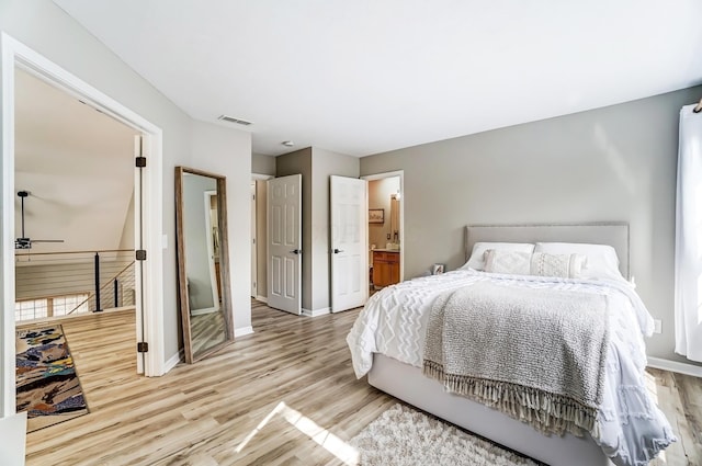 bedroom featuring ensuite bathroom, wood finished floors, visible vents, and baseboards