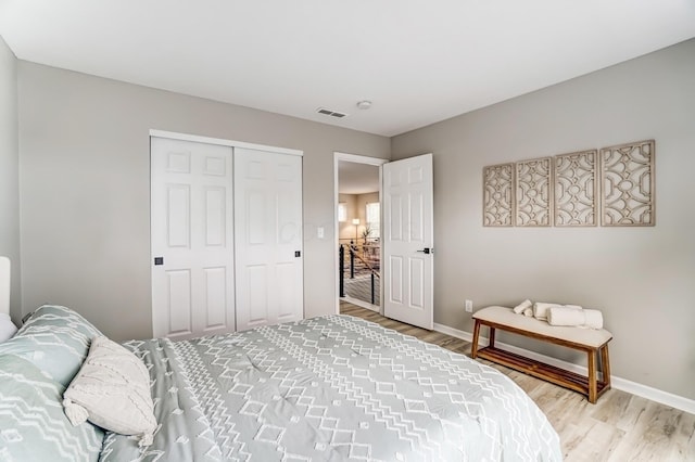 bedroom with light wood-type flooring, a closet, visible vents, and baseboards