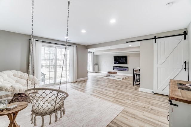 interior space featuring recessed lighting, light wood-style flooring, baseboards, and a barn door