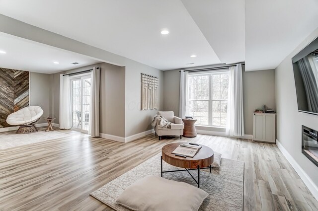 sitting room featuring light wood finished floors, recessed lighting, a glass covered fireplace, and baseboards