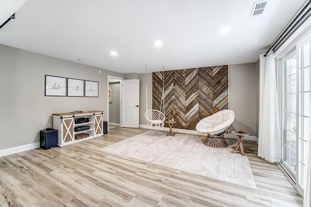 unfurnished room featuring light wood finished floors, recessed lighting, visible vents, an accent wall, and baseboards