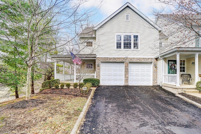 traditional-style house with an attached garage, stone siding, aphalt driveway, and a porch