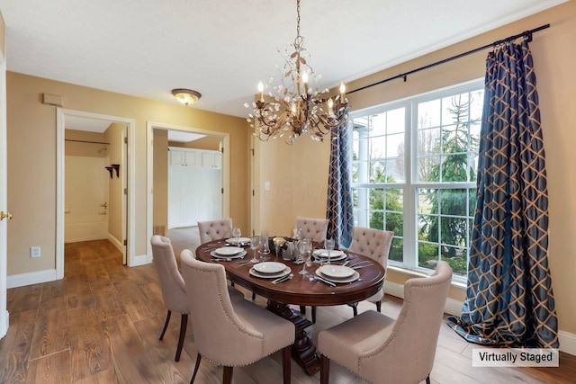 dining space with a notable chandelier, wood finished floors, and baseboards