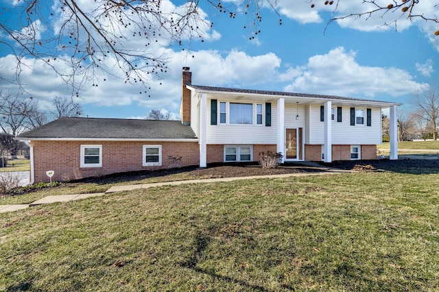 split foyer home with a front lawn, a chimney, and brick siding