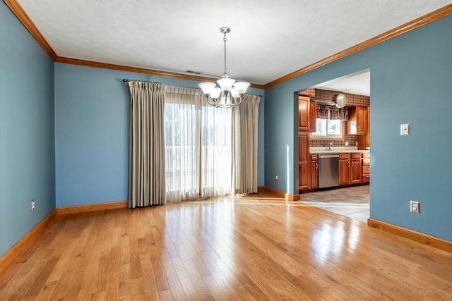 unfurnished dining area with baseboards, light wood-style floors, crown molding, and a notable chandelier