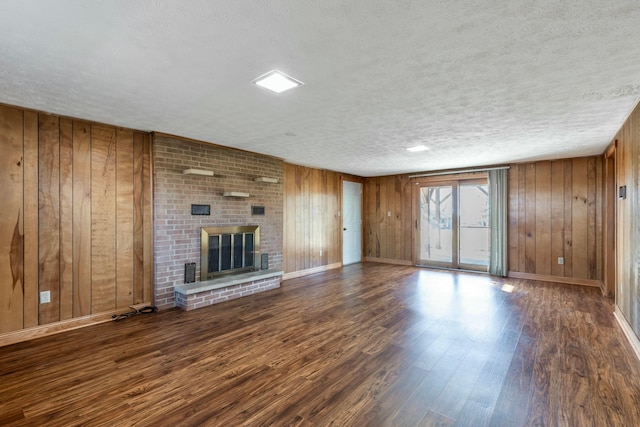 unfurnished living room featuring a textured ceiling, a fireplace, wood finished floors, and wooden walls