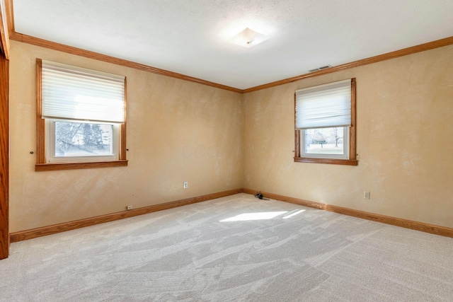 carpeted spare room featuring ornamental molding, visible vents, and baseboards