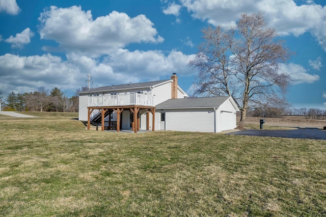 back of house with a garage, stairs, driveway, a yard, and a wooden deck