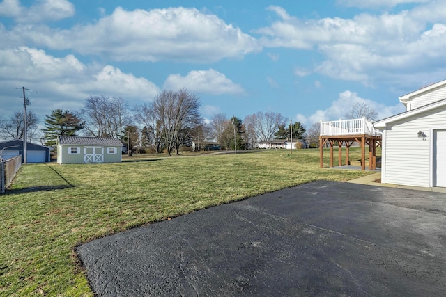 view of yard featuring an outbuilding, a deck, a storage unit, and a garage