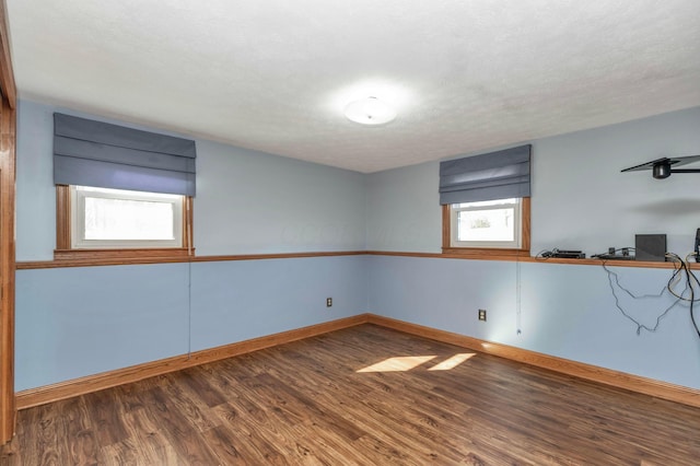 empty room featuring a textured ceiling, baseboards, and wood finished floors