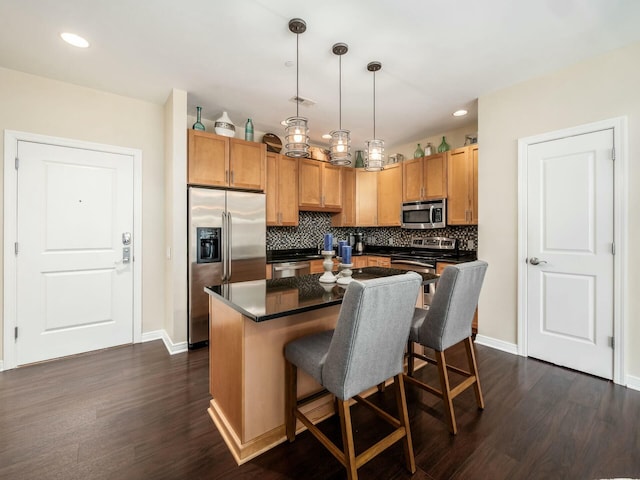 kitchen featuring a center island, stainless steel appliances, dark countertops, decorative backsplash, and a kitchen breakfast bar