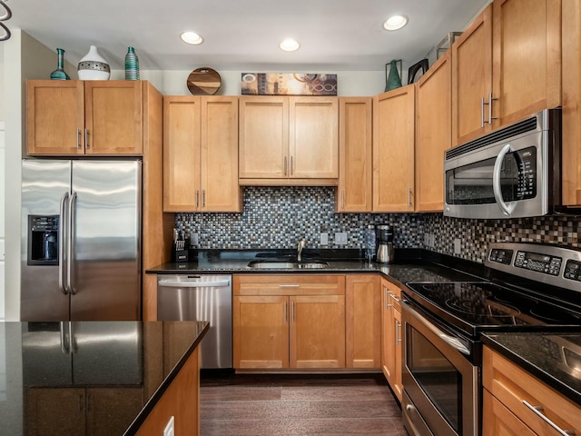 kitchen featuring appliances with stainless steel finishes, dark wood-style flooring, a sink, and decorative backsplash