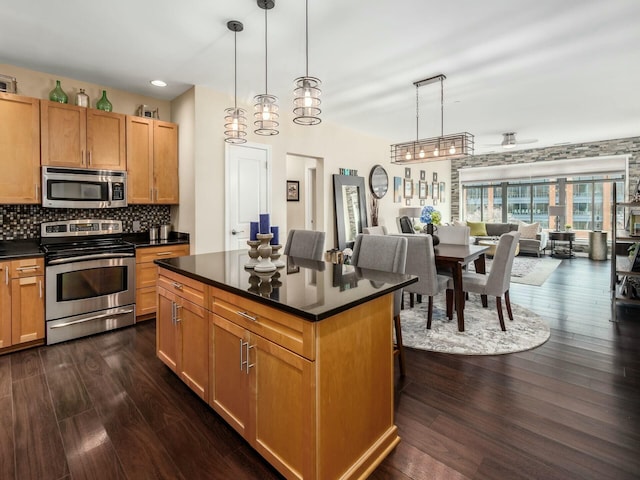 kitchen featuring tasteful backsplash, dark countertops, appliances with stainless steel finishes, open floor plan, and dark wood-type flooring