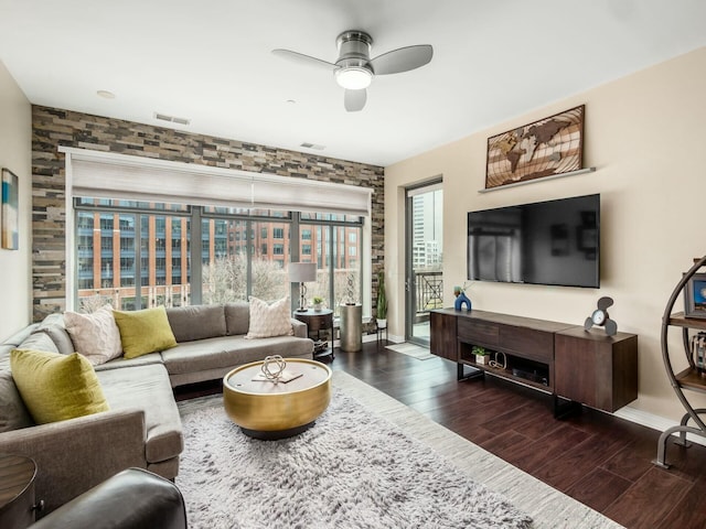 living room featuring baseboards, wood finished floors, visible vents, and a ceiling fan