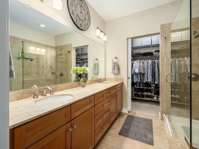 bathroom featuring double vanity, a sink, a shower stall, and a spacious closet