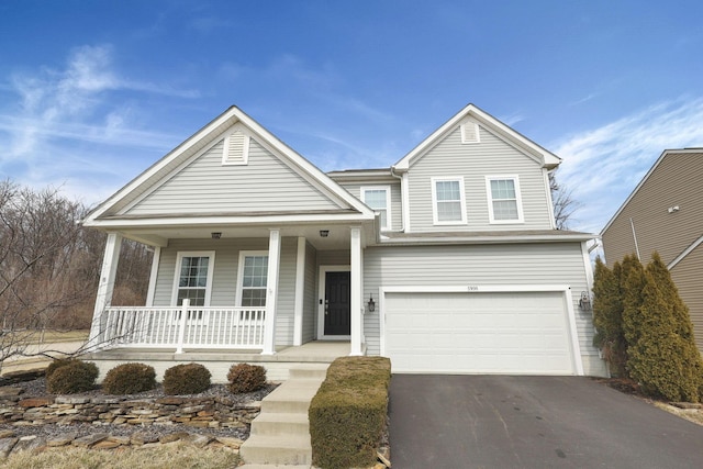 traditional home with a porch, an attached garage, and aphalt driveway