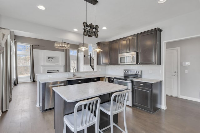 kitchen with tasteful backsplash, a center island, a peninsula, stainless steel appliances, and a sink