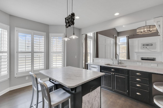 kitchen featuring light countertops, a kitchen island, a sink, and dark cabinets