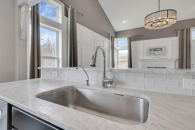 kitchen featuring hanging light fixtures, a sink, vaulted ceiling, light countertops, and a notable chandelier