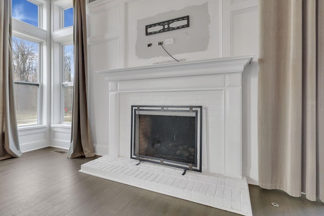 room details with visible vents, a fireplace, baseboards, and wood finished floors