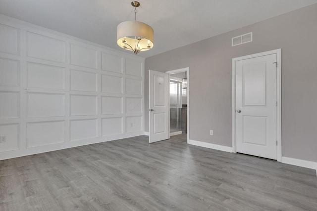 interior space with wood finished floors, visible vents, and a decorative wall