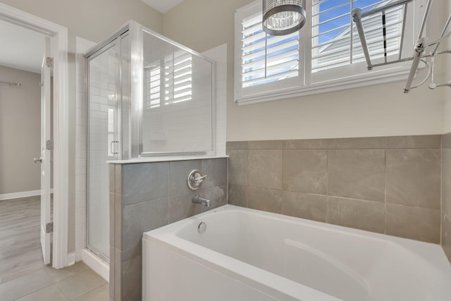 bathroom with a stall shower, tile patterned flooring, and a bath