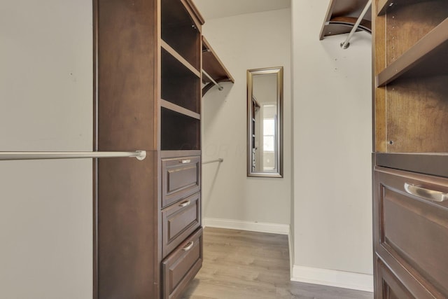 walk in closet with light wood-style floors